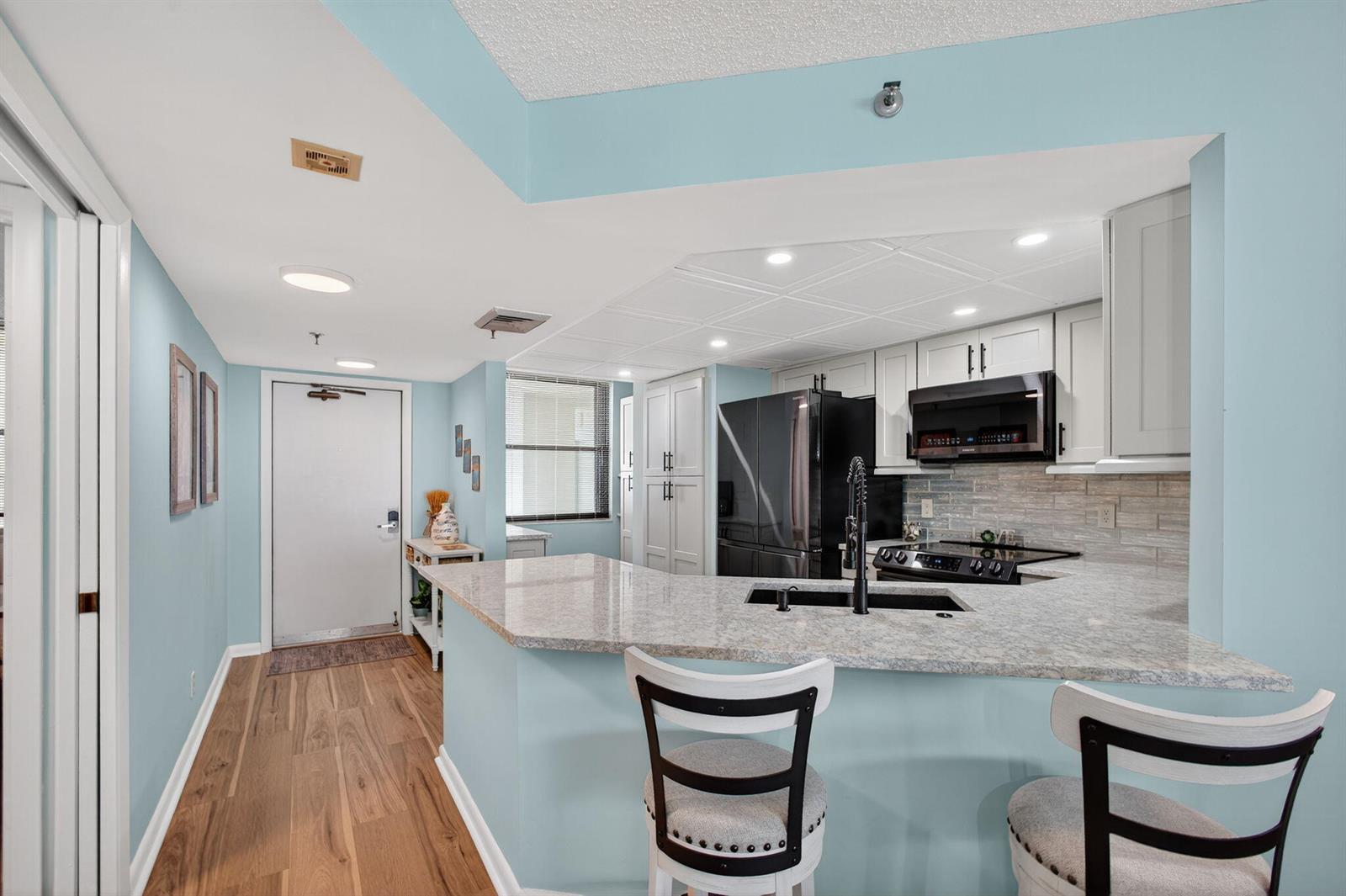 A kitchen with light blue walls, granite countertops, white cabinets, and a breakfast bar — 9650 S Ocean Drive # 302, Jensen Beach FL 34957, JENSEN BEACH, FL