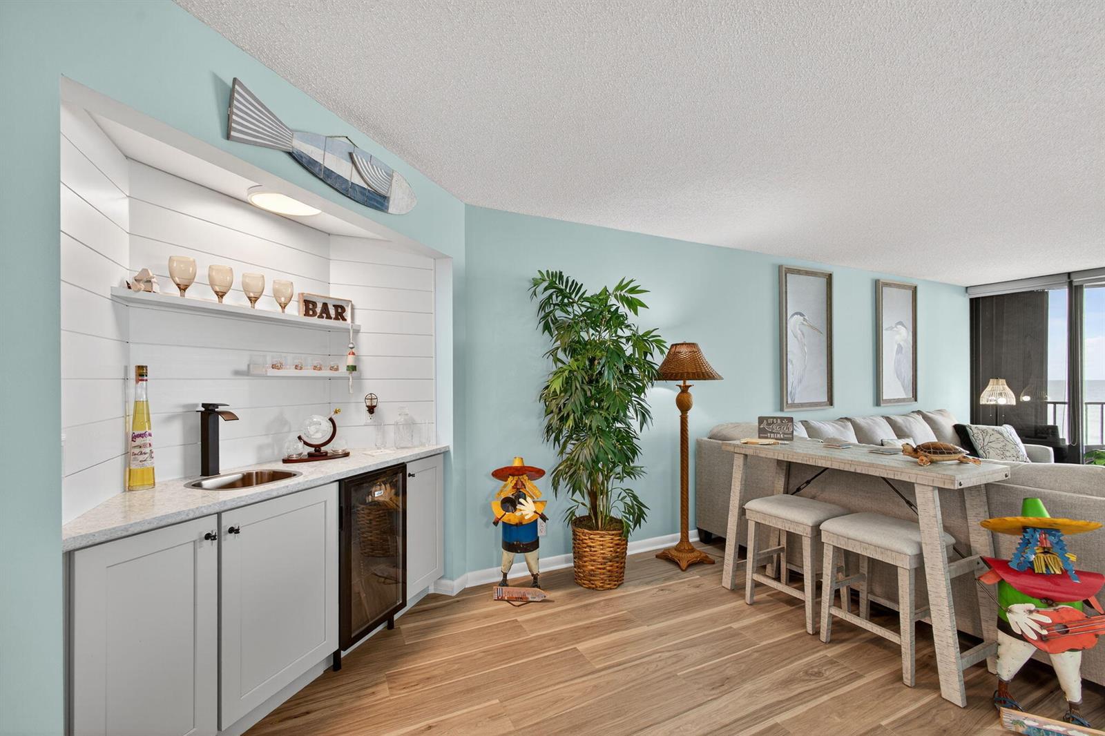 A wet bar with white shiplap walls and grey cabinets sits beside a dining area — 9650 S Ocean Drive # 302, Jensen Beach FL 34957, JENSEN BEACH, FL