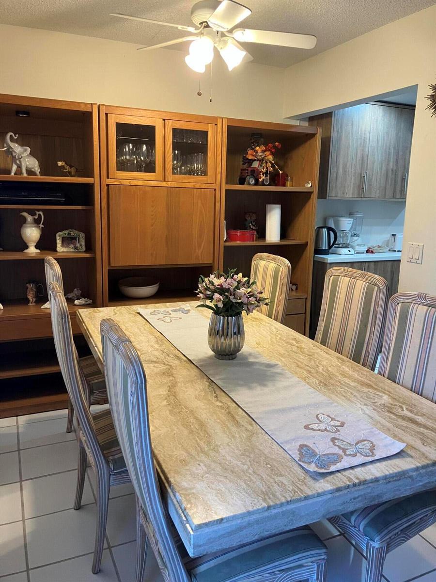 A dining room features a stone-topped table, striped chairs, and a large wooden wall unit — 283 Durham H E # 283, Deerfield Beach FL 33442, DEERFIELD BEACH, FL