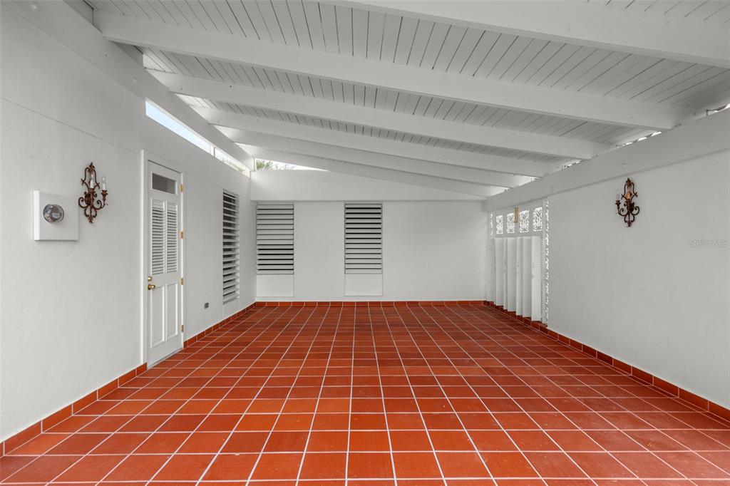 An empty sunroom features white walls, a vaulted ceiling, and red tile flooring — AF7 Villa Franca BARCELONA ST, HUMACAO, PR