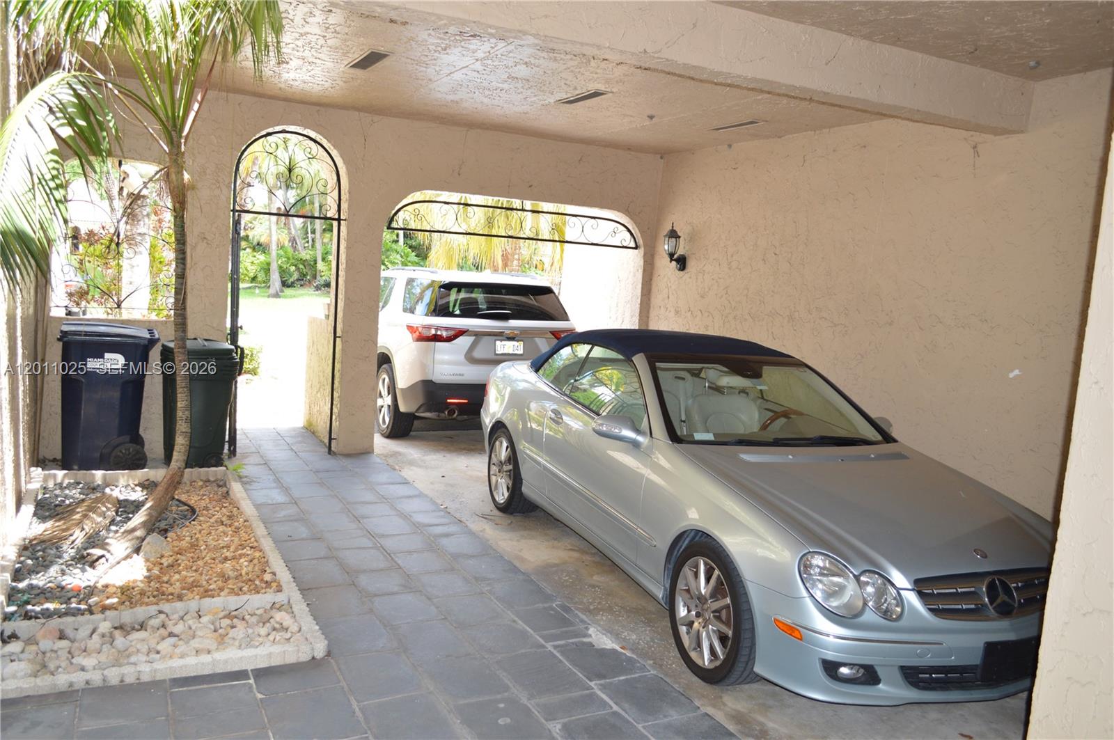 A silver convertible and a white SUV are parked in a covered outdoor carport — 3932 Estepona Ave, Doral FL 33178, DORAL, FL