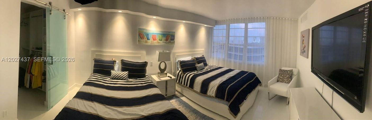 A bedroom features two beds with navy and white striped bedding and a large television — 100 Lincoln Rd # 1535, Miami Beach FL 33139, MIAMI BEACH, FL