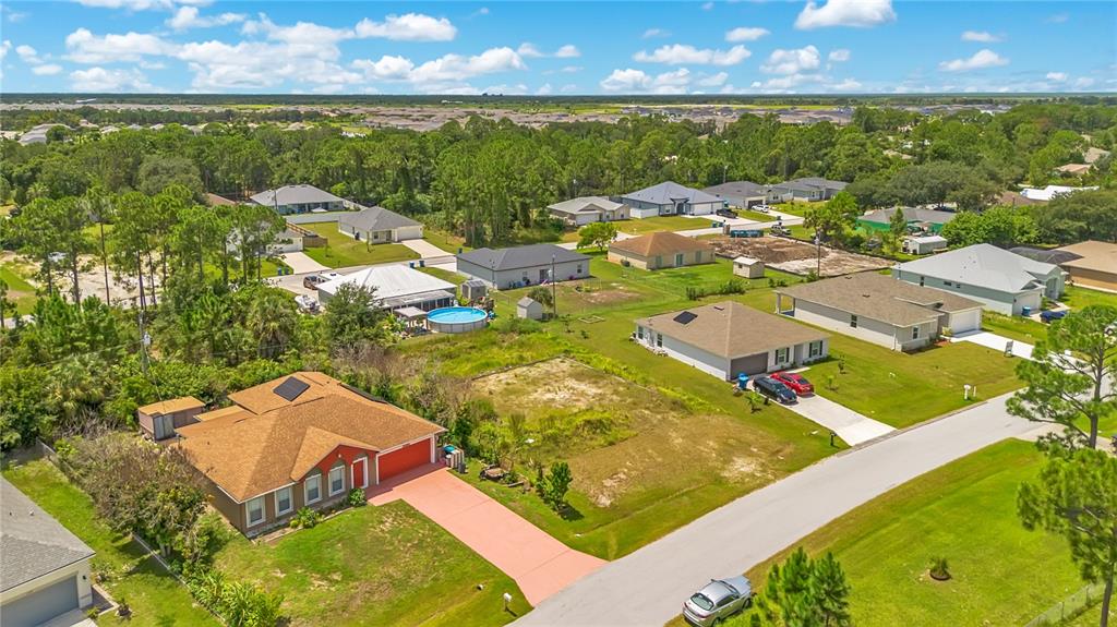 An aerial view shows a red house with a brown roof next to a vacant lot — 1358 TORDIRA STREET SE, PALM BAY, FL
