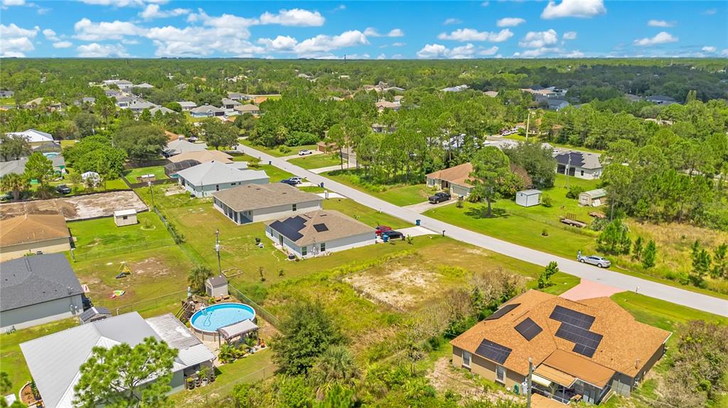 An aerial view shows several suburban houses with solar panels and a backyard swimming pool — 1358 TORDIRA STREET SE, PALM BAY, FL