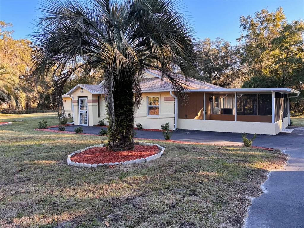 A single-story house with a palm tree in the front yard and a screened porch — 12989 NW HIGHWAY 225, REDDICK, FL