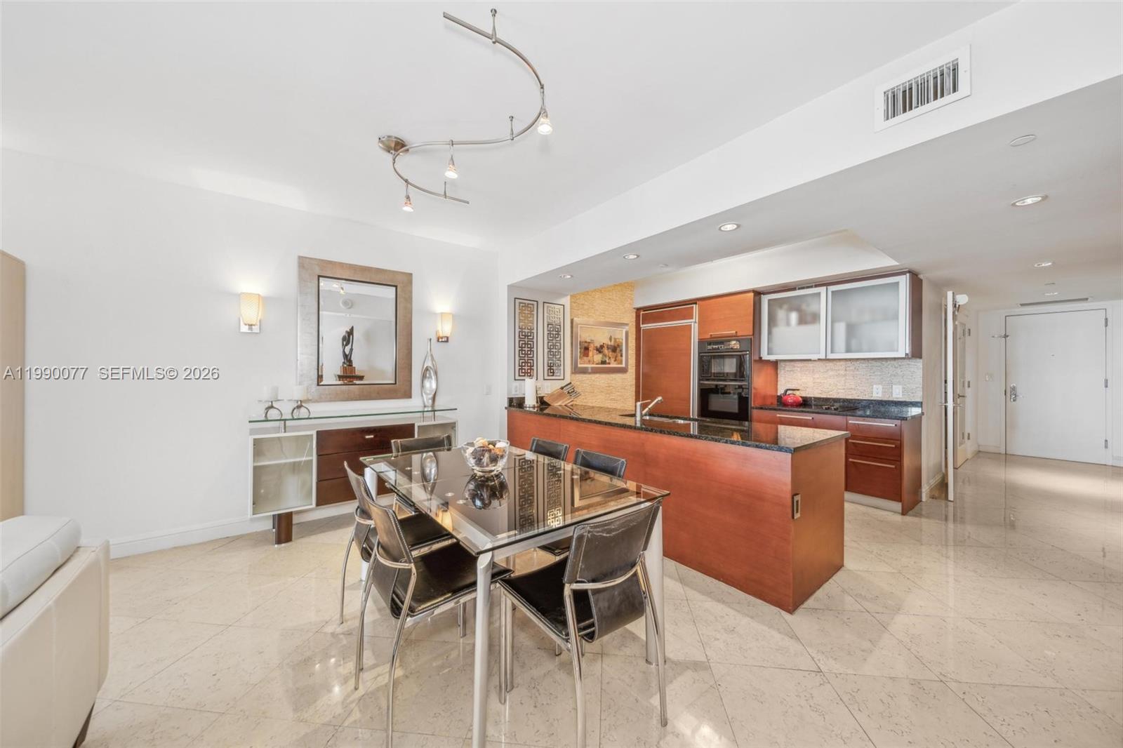 A modern kitchen and dining area feature dark wood cabinetry, granite countertops, and tile flooring — 1830 S Ocean Dr # 3111, Hallandale Beach FL 33009, HALLANDALE BEACH, FL