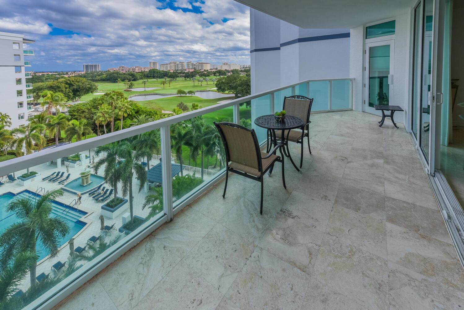 A balcony with stone flooring, patio furniture, and views of a pool and golf course — 550 SE Mizner Boulevard # B702, Boca Raton FL 33432, BOCA RATON, FL