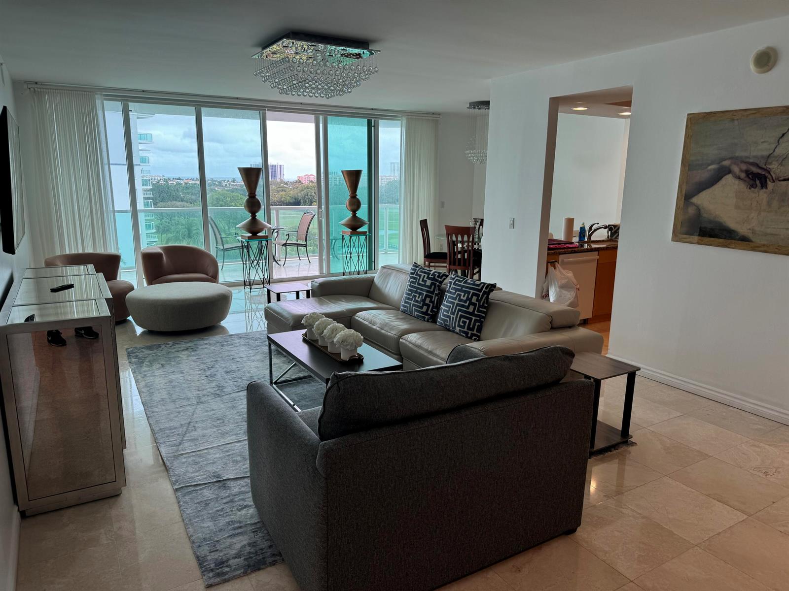 A living room with a sectional sofa, area rug, and floor-to-ceiling windows overlooking a balcony — 550 SE Mizner Boulevard # B702, Boca Raton FL 33432, BOCA RATON, FL
