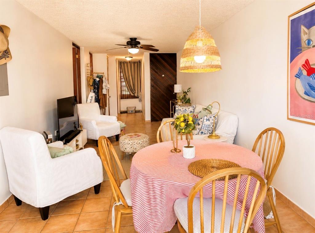 A dining area with a round table and chairs sits in front of a living room — PRINCIPAL CASA DEL MAR II UNIT 2705, RIO GRANDE, PR