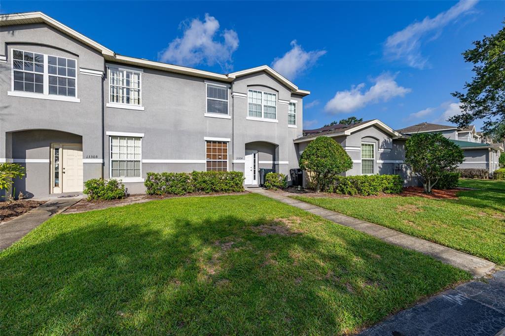 A two-story gray townhouse with a front lawn, walkways, and two separate entry doors — 13304 SUMMERTON DRIVE, ORLANDO, FL