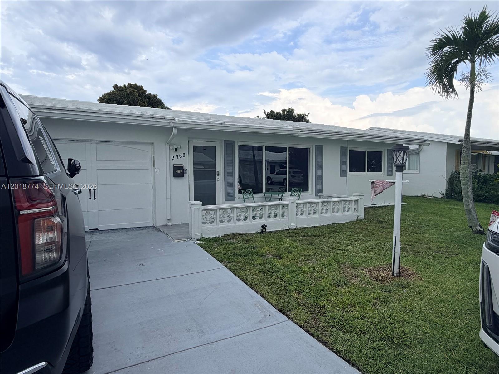 A single-story white house features a garage, a concrete driveway, and a decorative low wall — 2960 NW 1st Dr, Pompano Beach FL 33064, POMPANO BEACH, FL