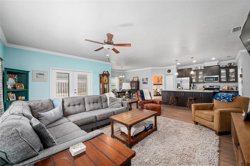 An open-concept living room and kitchen feature a gray sectional, wood furniture, and light-blue walls — 16635 NW 193RD TERRACE, HIGH SPRINGS, FL