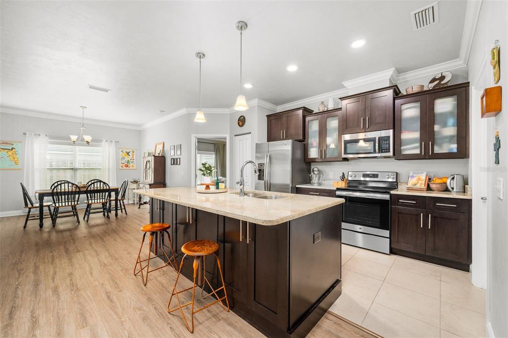 A kitchen with dark wood cabinets, a granite-topped island, and stainless steel appliances — 16635 NW 193RD TERRACE, HIGH SPRINGS, FL