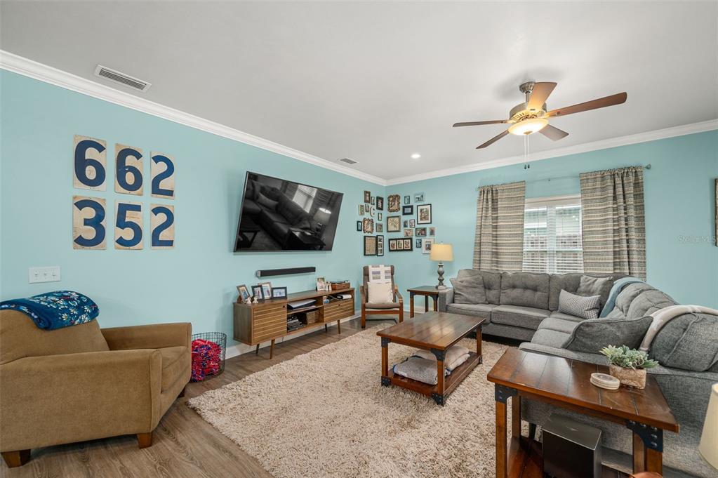 A living room features light blue walls, a gray sectional sofa, and a wood media console — 16635 NW 193RD TERRACE, HIGH SPRINGS, FL