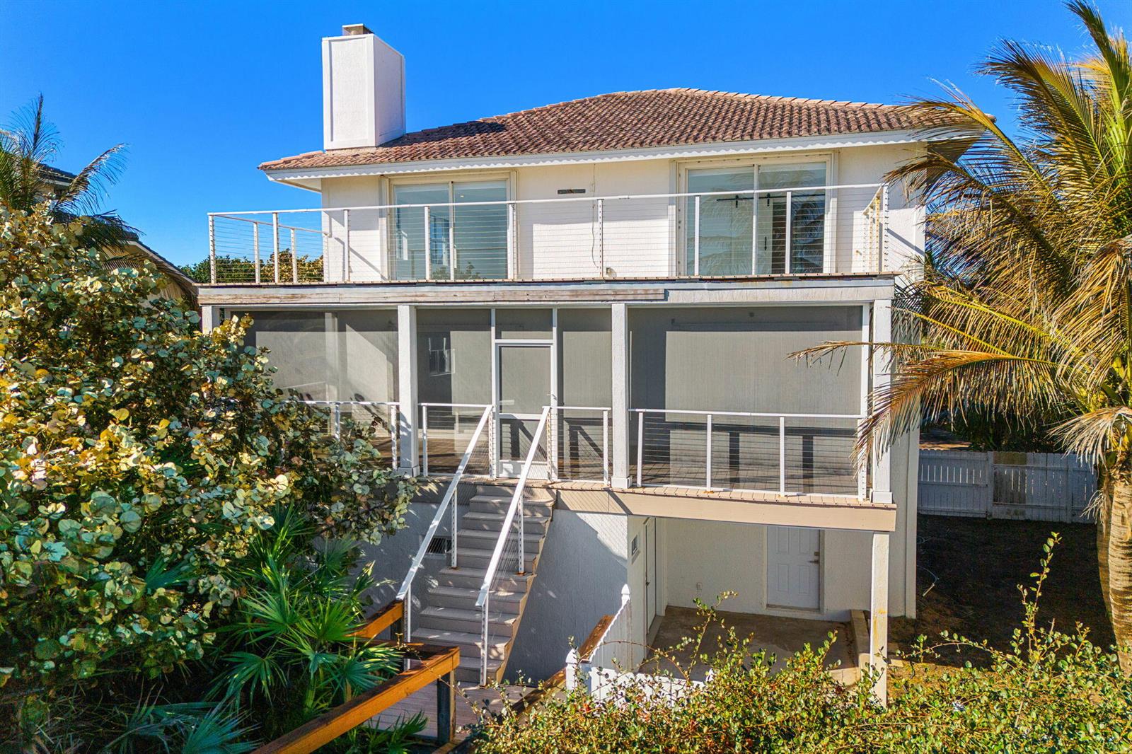 Exterior view of a two-story house with a screened-in porch, balcony, and outdoor staircase — 9085 S Highway A1a, Melbourne Beach FL 32951, MELBOURNE BEACH, FL
