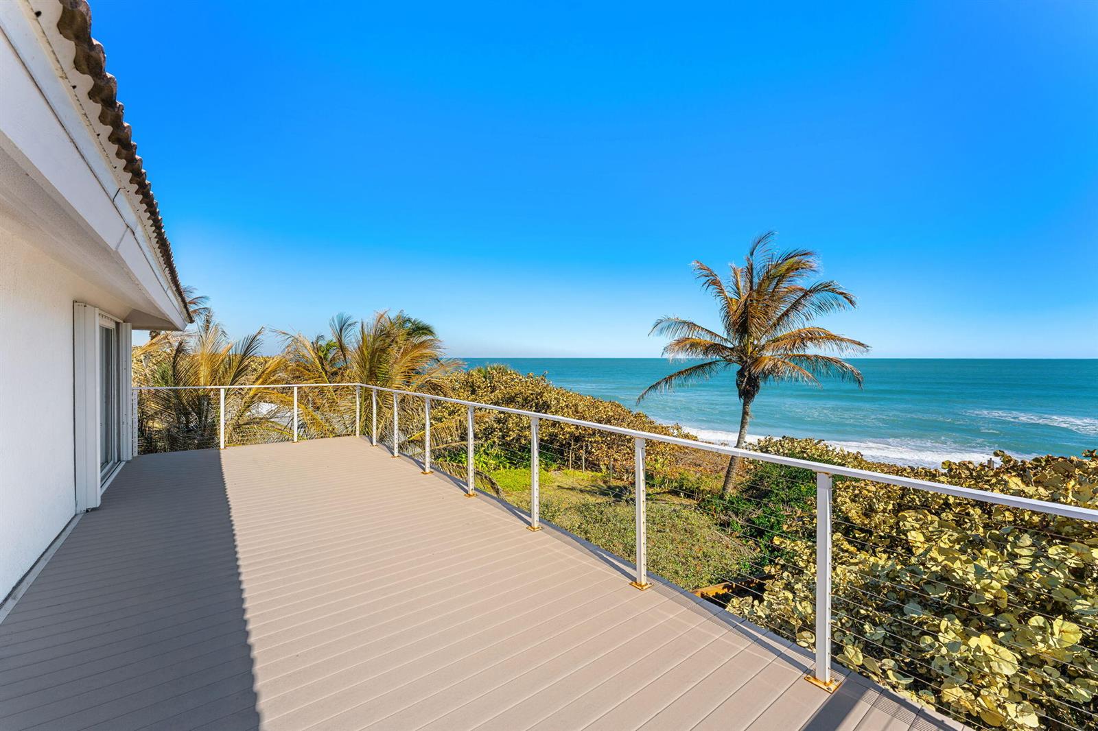 An elevated outdoor deck with a white railing overlooks the ocean and coastal vegetation — 9085 S Highway A1a, Melbourne Beach FL 32951, MELBOURNE BEACH, FL