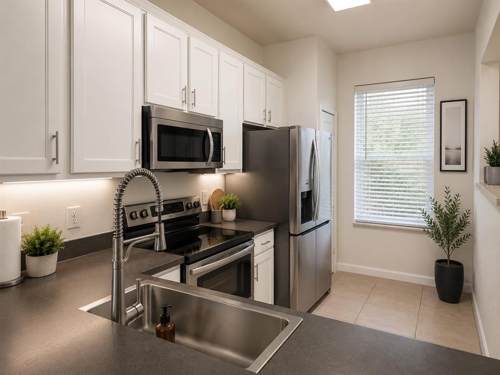 A kitchen features white cabinets, stainless steel appliances, dark countertops, and a stainless steel sink — 2761 RETREAT VIEW CIRCLE, SANFORD, FL