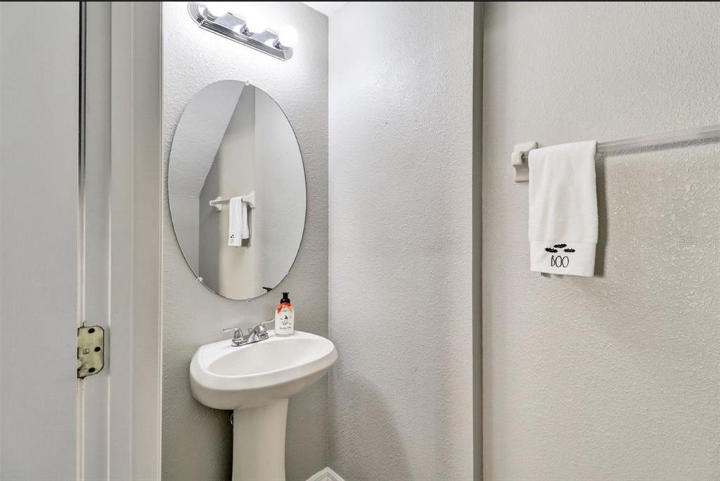 A small powder room features a white pedestal sink, an oval mirror, and gray walls — 2761 RETREAT VIEW CIRCLE, SANFORD, FL