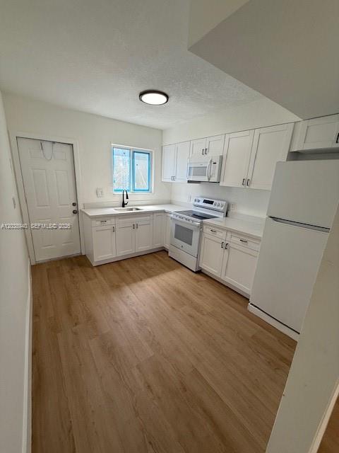 A kitchen features white cabinets, light wood-look flooring, a white refrigerator, and a window — 1123 N 17th Ct, Hollywood FL 33020, HOLLYWOOD, FL