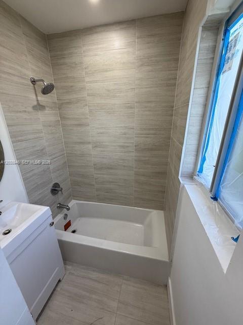 A bathroom features a white bathtub, a vanity, and light-colored wood-look wall tiles — 1123 N 17th Ct, Hollywood FL 33020, HOLLYWOOD, FL