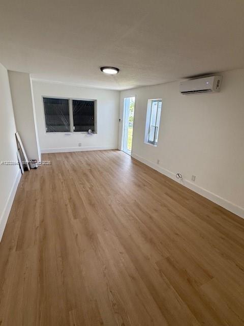 An empty room features light wood-look flooring, white walls, a mini-split unit, and two windows — 1123 N 17th Ct, Hollywood FL 33020, HOLLYWOOD, FL