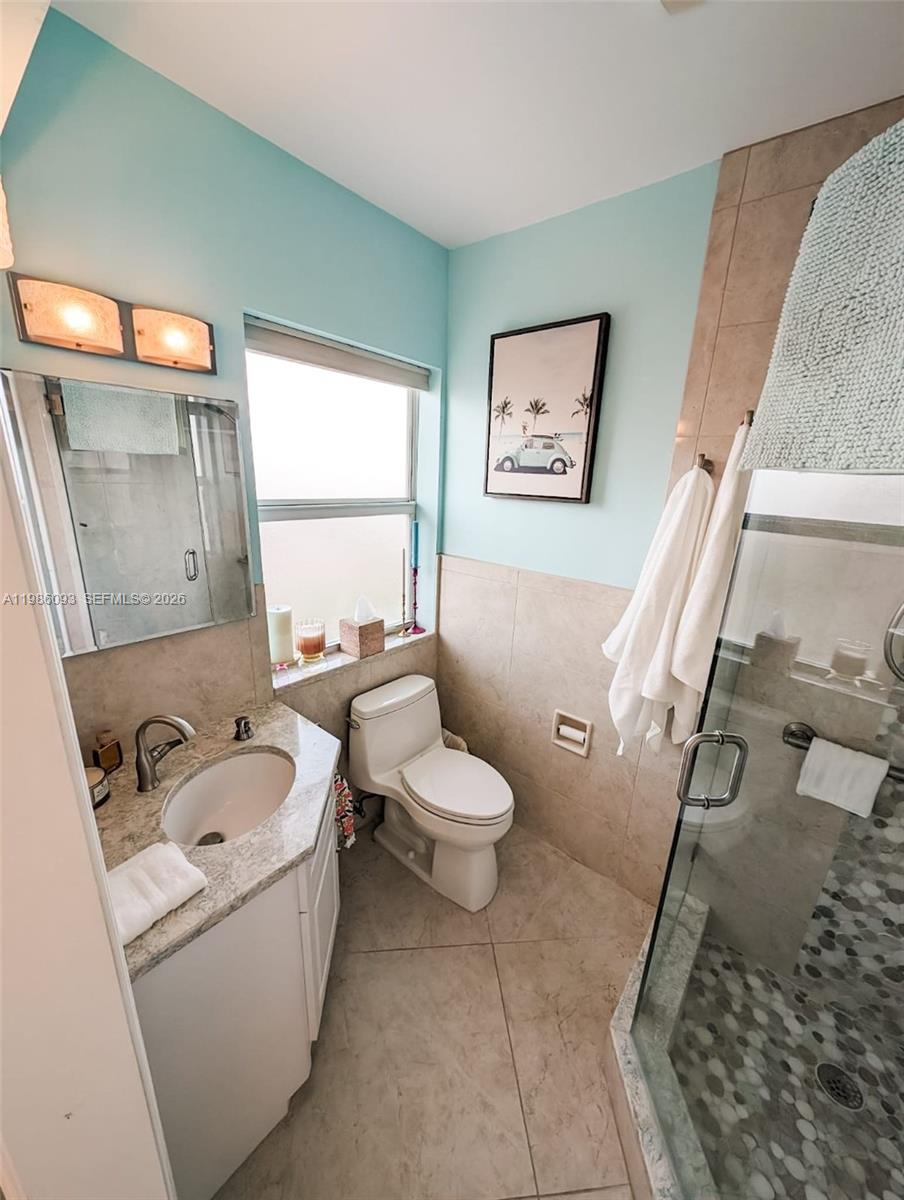 A bathroom features a vanity, toilet, and a glass-enclosed shower with pebble-tiled flooring — 1501 S Surf Rd # 21, Hollywood FL 33019, HOLLYWOOD, FL