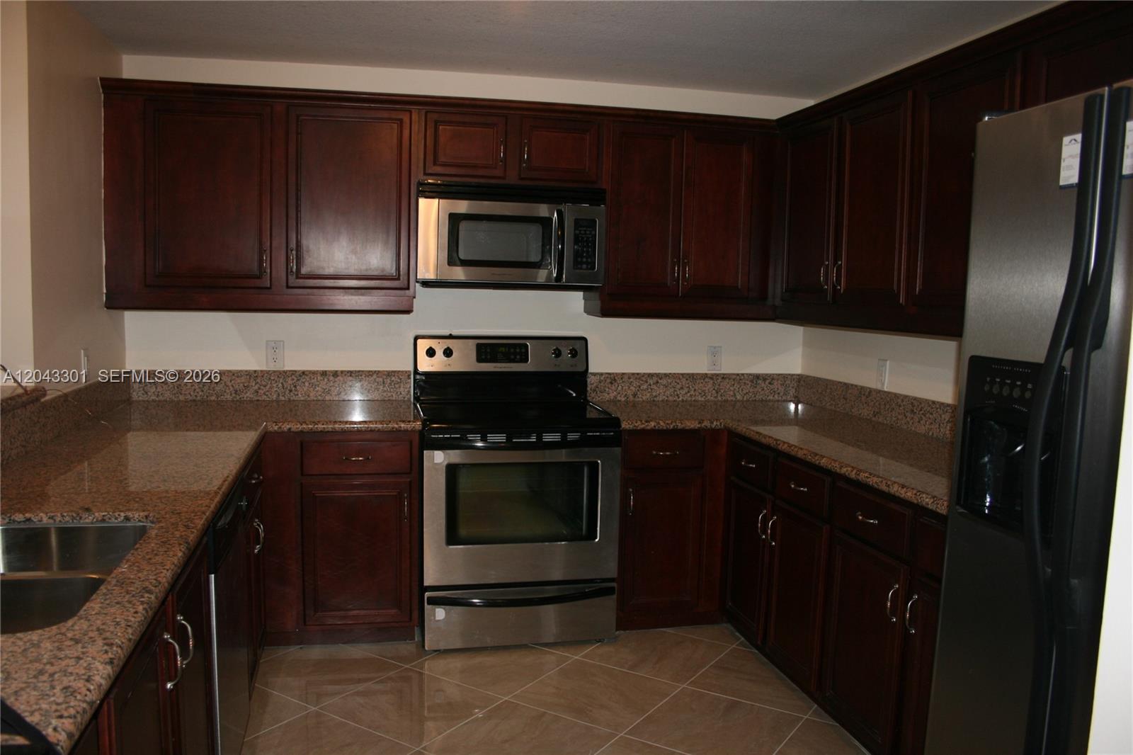 A kitchen features granite countertops, dark wood cabinets, and a stainless steel dishwasher — 5271 SW 8th St # 216, Miami FL 33134, MIAMI, FL