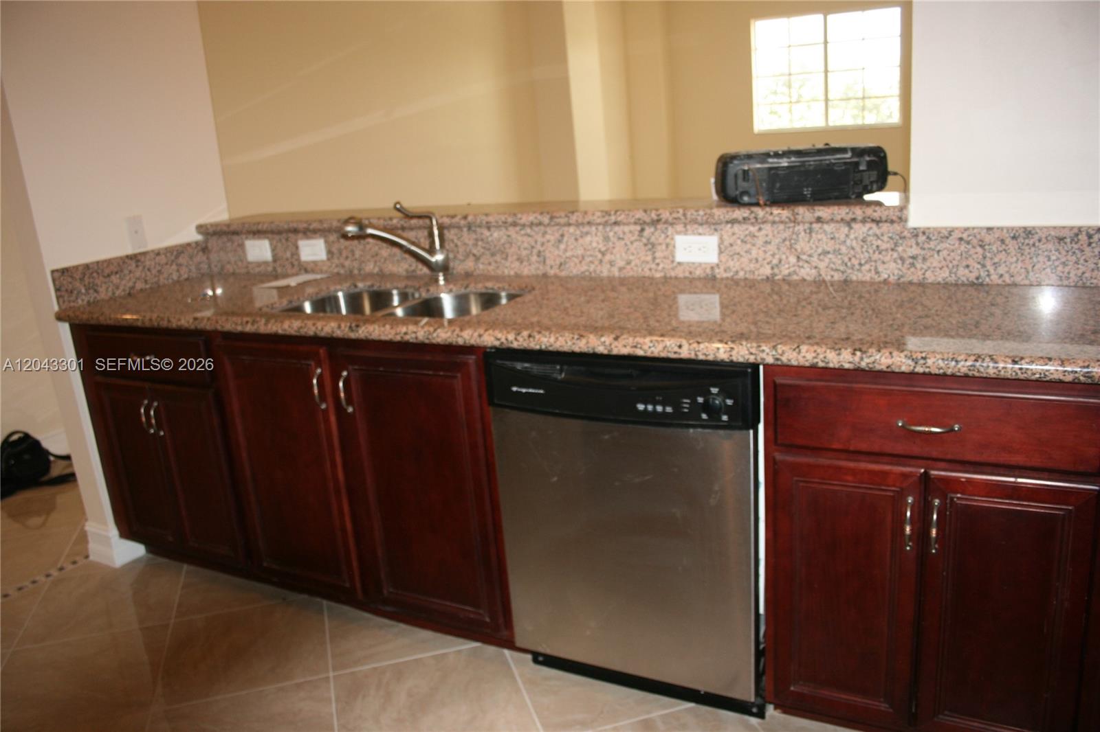 An open living area features beige tile flooring and a kitchen with dark wood cabinets — 5271 SW 8th St # 216, Miami FL 33134, MIAMI, FL