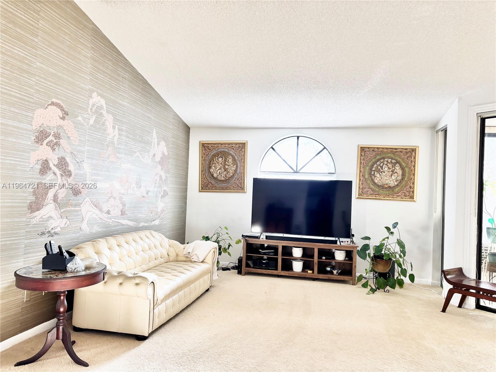 A living room features a tufted cream sofa, a television console, and decorative wall art — 5258 Europa Dr # H, Boynton Beach FL 33437, BOYNTON BEACH, FL