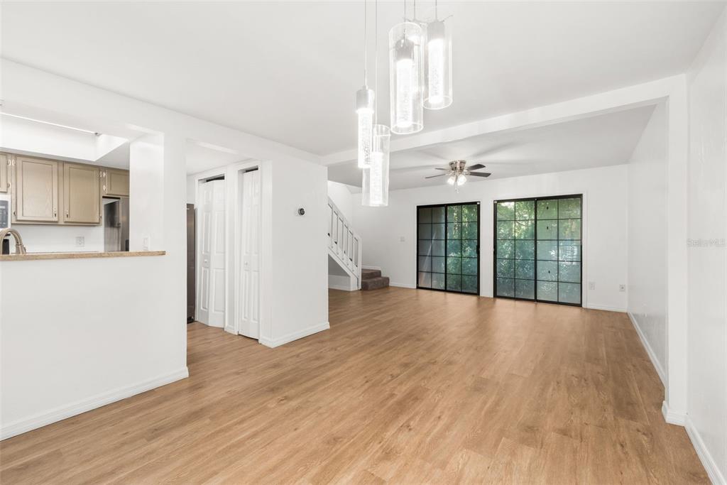 A bright living room features wood-look flooring, a modern pendant light, and sliding glass doors — 825 SW 55TH TERRACE, GAINESVILLE, FL