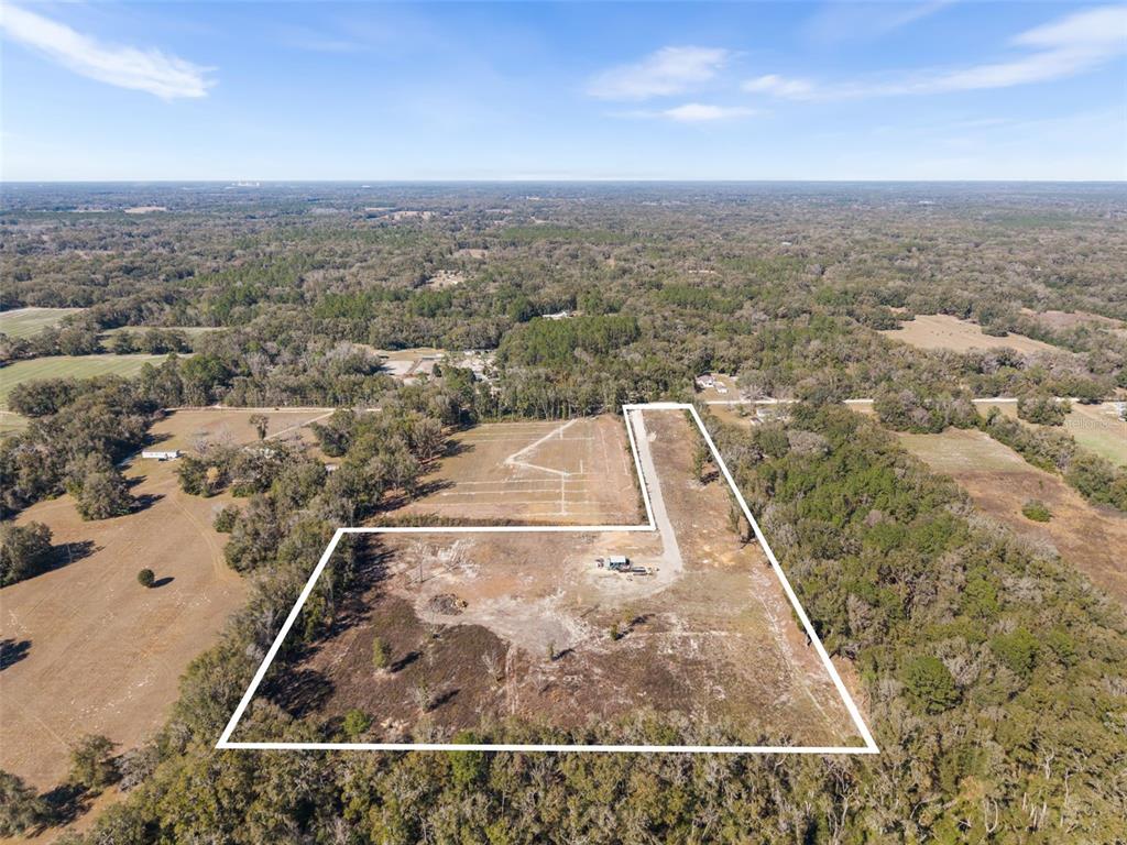 An aerial view shows a large, cleared rectangular plot of land surrounded by dense forest — 17807 SW 83RD AVENUE, ARCHER, FL