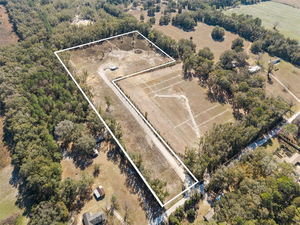 An aerial view shows a large, L-shaped plot of cleared land surrounded by trees — 17807 SW 83RD AVENUE, ARCHER, FL