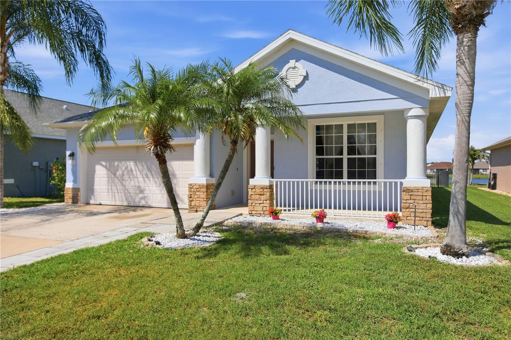 A light blue single-story house features a two-car garage, stone accents, and a front porch — 12512 23RD STREET E, PARRISH, FL