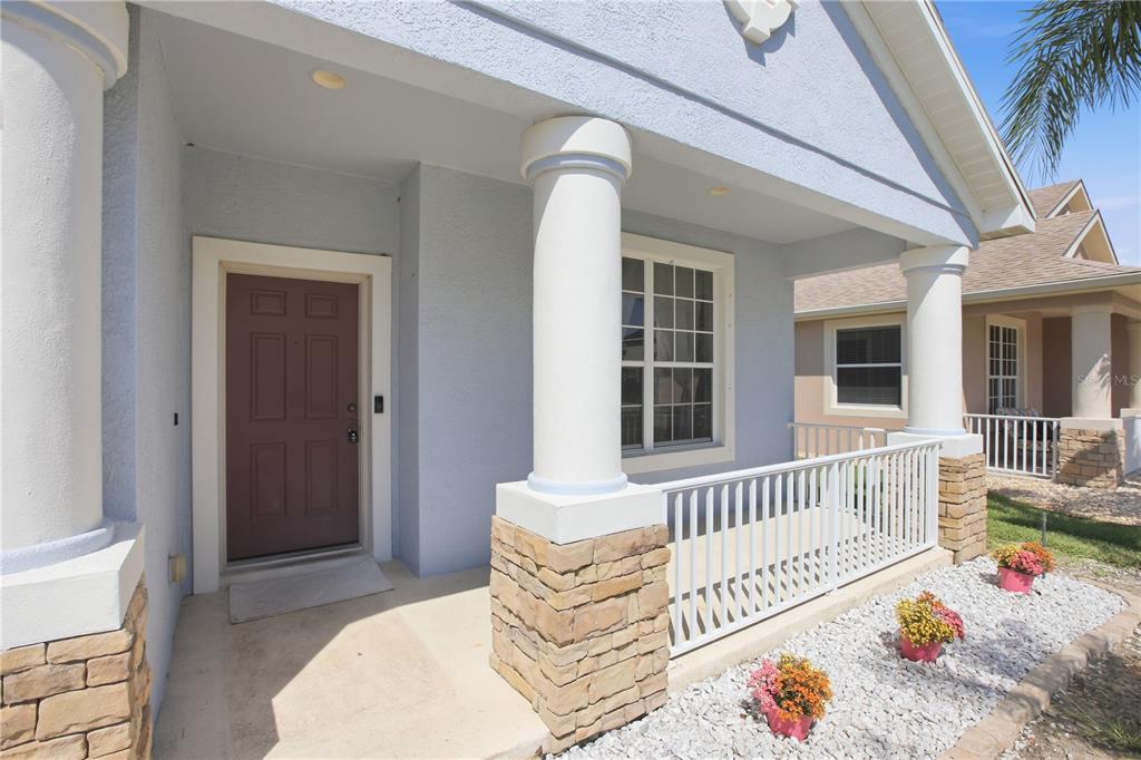 A light blue house exterior features a covered porch with white columns and stone bases — 12512 23RD STREET E, PARRISH, FL