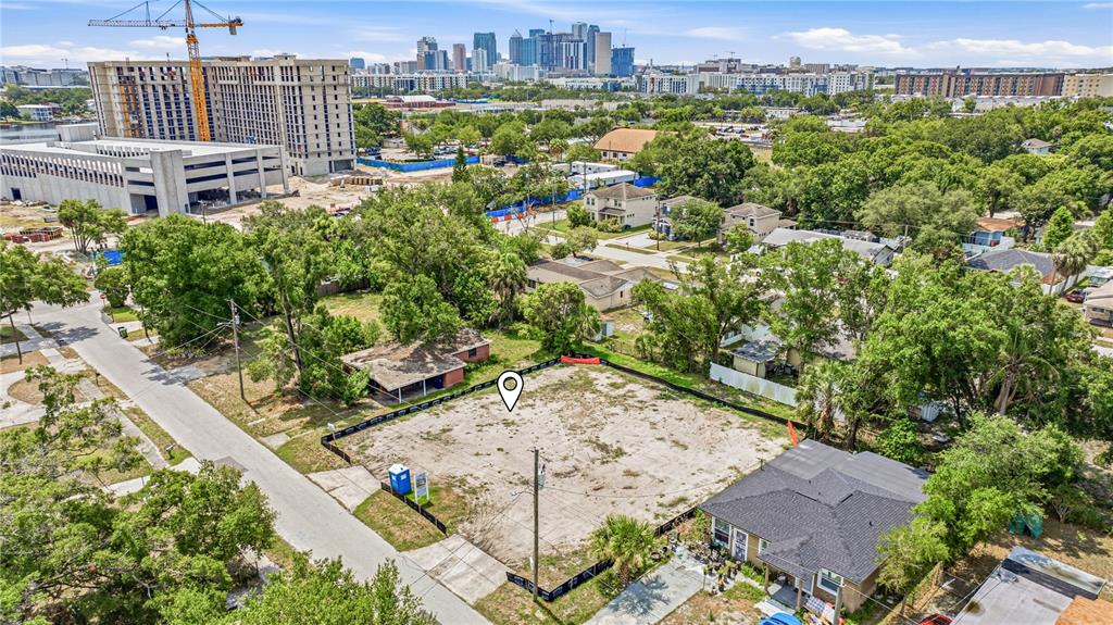 An aerial view shows a vacant, fenced-in residential lot situated in a city neighborhood — 1710 W SAINT CONRAD STREET, TAMPA, FL