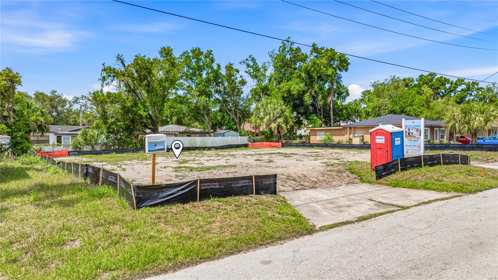 A vacant, fenced-in residential lot features a portable toilet and a real estate sign — 1710 W SAINT CONRAD STREET, TAMPA, FL