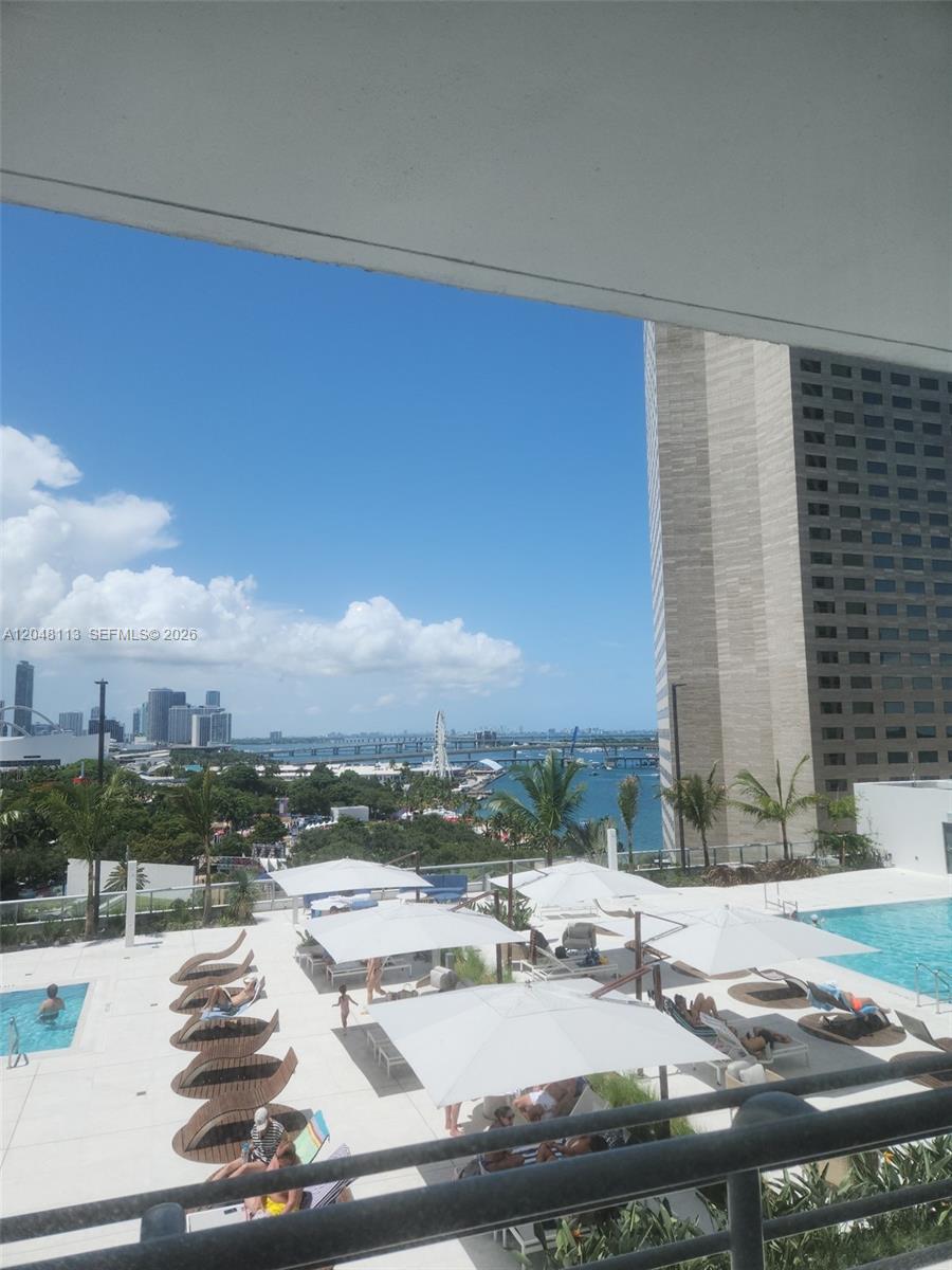 A high-angle view shows a pool deck with lounge chairs, umbrellas, and a city skyline — 325 S Biscayne Blvd # 1420, Miami FL 33131, MIAMI, FL