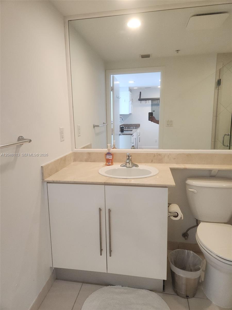 A bathroom features a white vanity with a beige countertop, a mirror, and a toilet — 325 S Biscayne Blvd # 1420, Miami FL 33131, MIAMI, FL