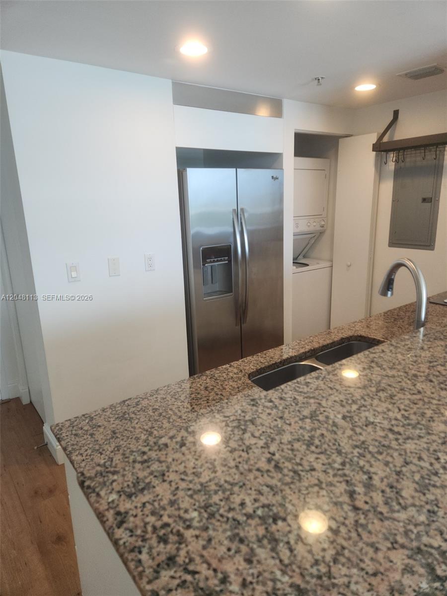 A kitchen features a granite countertop, stainless steel refrigerator, and an in-unit stacked laundry closet — 325 S Biscayne Blvd # 1420, Miami FL 33131, MIAMI, FL