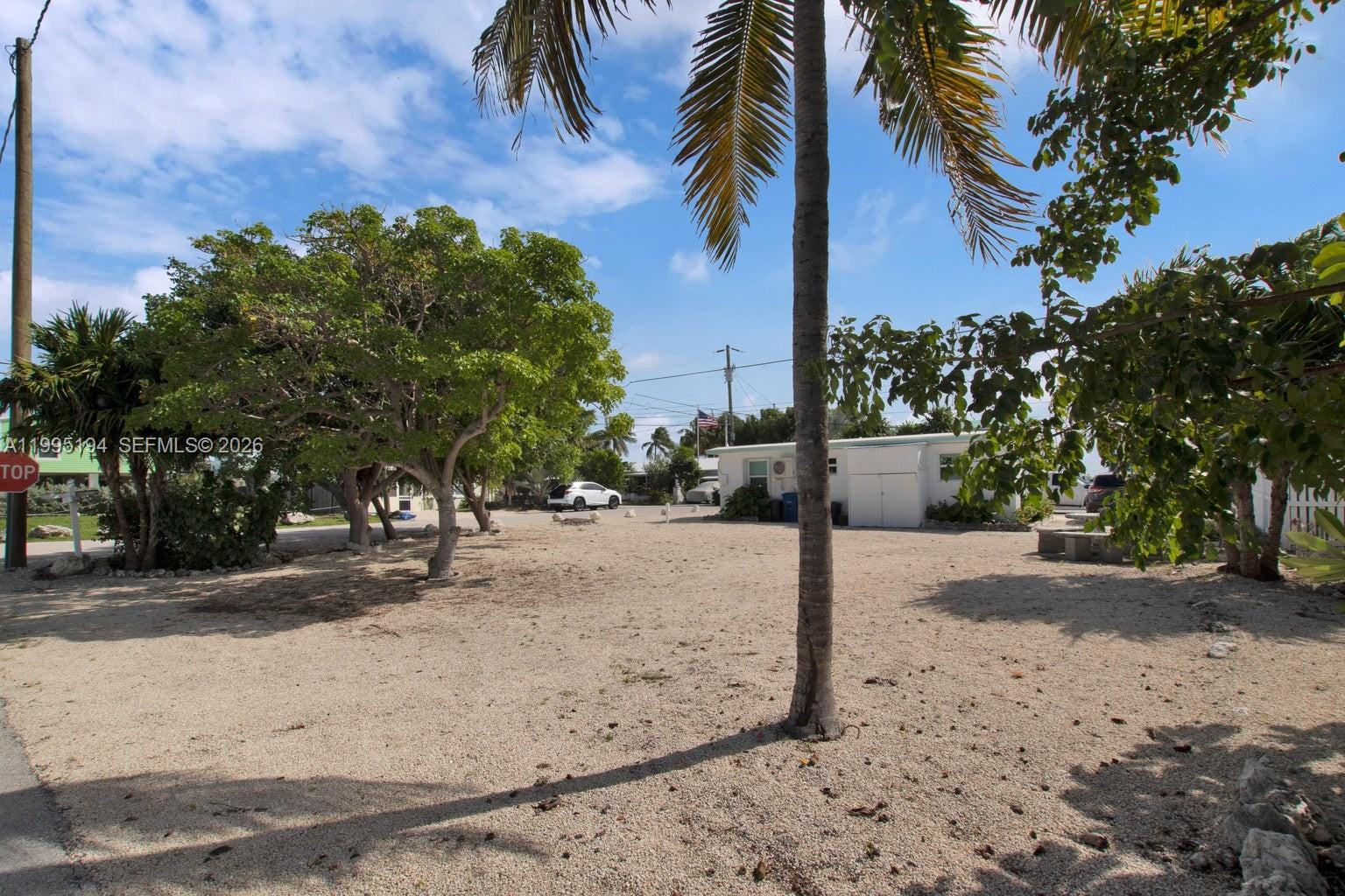 A gravel lot features several trees, a palm tree, and a small white building — Lot 70 5th Ave Ocean, Marathon FL 33050, MARATHON, FL