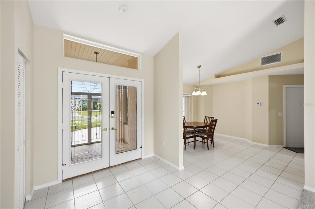 An entryway with white tile floors leads to a dining area with a vaulted ceiling — 63 CLUBHOUSE ROAD, ROTONDA WEST, FL