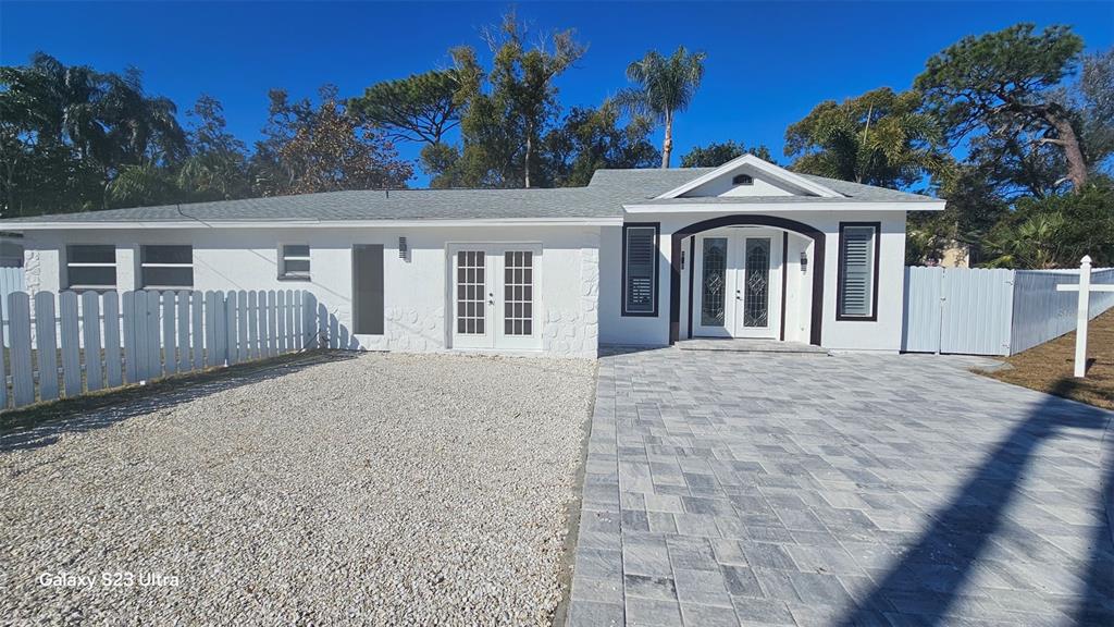 A white single-story house features a paved driveway, gravel area, and two sets of doors — 1092 N FLORIDA AVENUE, TARPON SPRINGS, FL