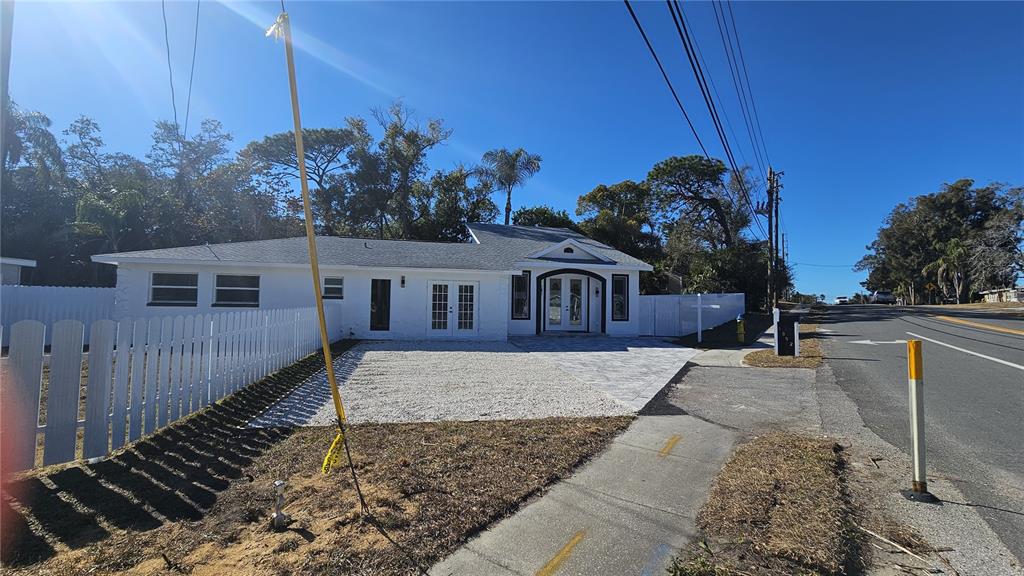 A white single-story house features a gravel driveway, a paved walkway, and a white fence — 1092 N FLORIDA AVENUE, TARPON SPRINGS, FL