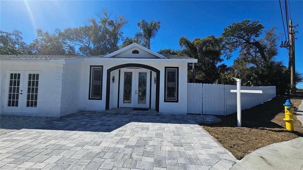 A white house with a paved driveway, double front doors, and a white privacy fence — 1092 N FLORIDA AVENUE, TARPON SPRINGS, FL
