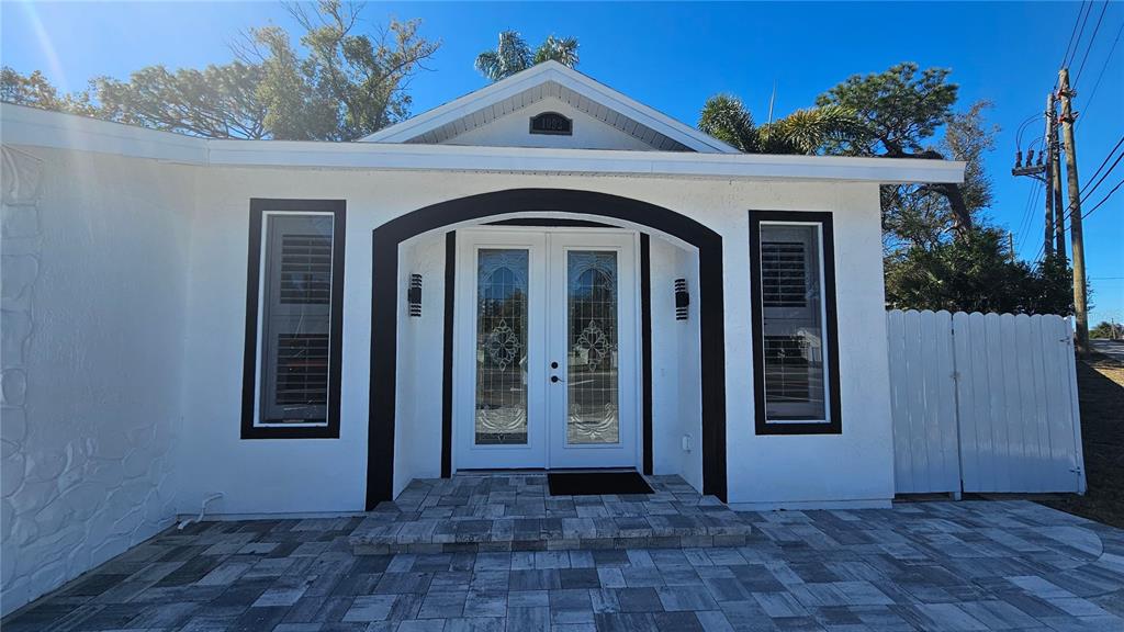 The exterior of a white house features a black-trimmed arched entryway and double glass doors — 1092 N FLORIDA AVENUE, TARPON SPRINGS, FL