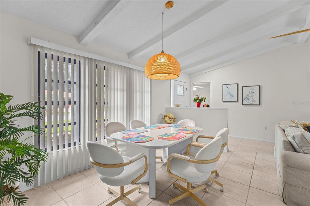 A dining area features a white table with six chairs under a woven pendant light — 4308 PASADENA CIRCLE, SARASOTA, FL