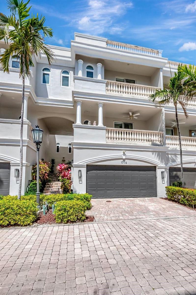 A three-story white townhouse features a gray garage door, balconies, and palm trees — 1776 Bay Drive, Pompano Beach FL 33062, POMPANO BEACH, FL