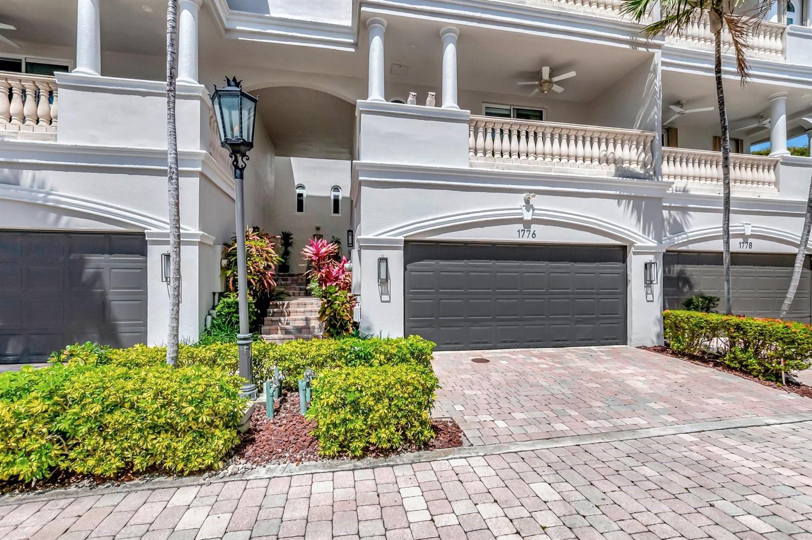 A multi-story building exterior features gray garage doors, a stone staircase, and landscaped bushes — 1776 Bay Drive, Pompano Beach FL 33062, POMPANO BEACH, FL