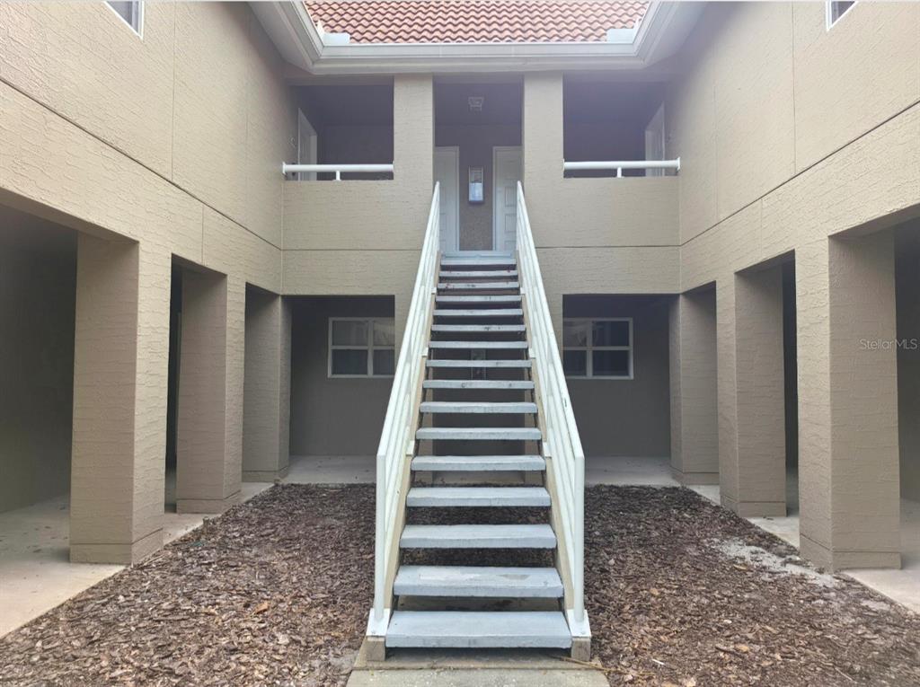 A central staircase leads to the upper level of a tan, multi-unit residential building — 15215 AMBERLY DRIVE UNIT 907, TAMPA, FL