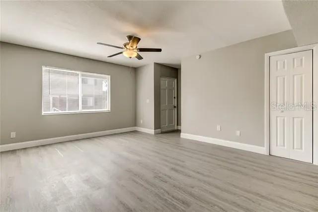 A living room with light gray walls, wood-look flooring, a ceiling fan, and a closet — 300 6TH STREET N UNIT W2, SAFETY HARBOR, FL